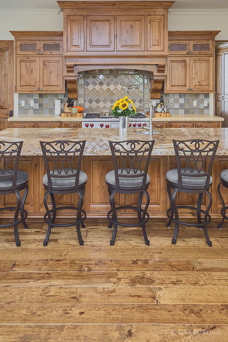 Wide Plank Hand-Scraped Hickory Hardwood Floor by Oak and Broad | wrought-iron style barstools in rustic kitchen with sunflowers