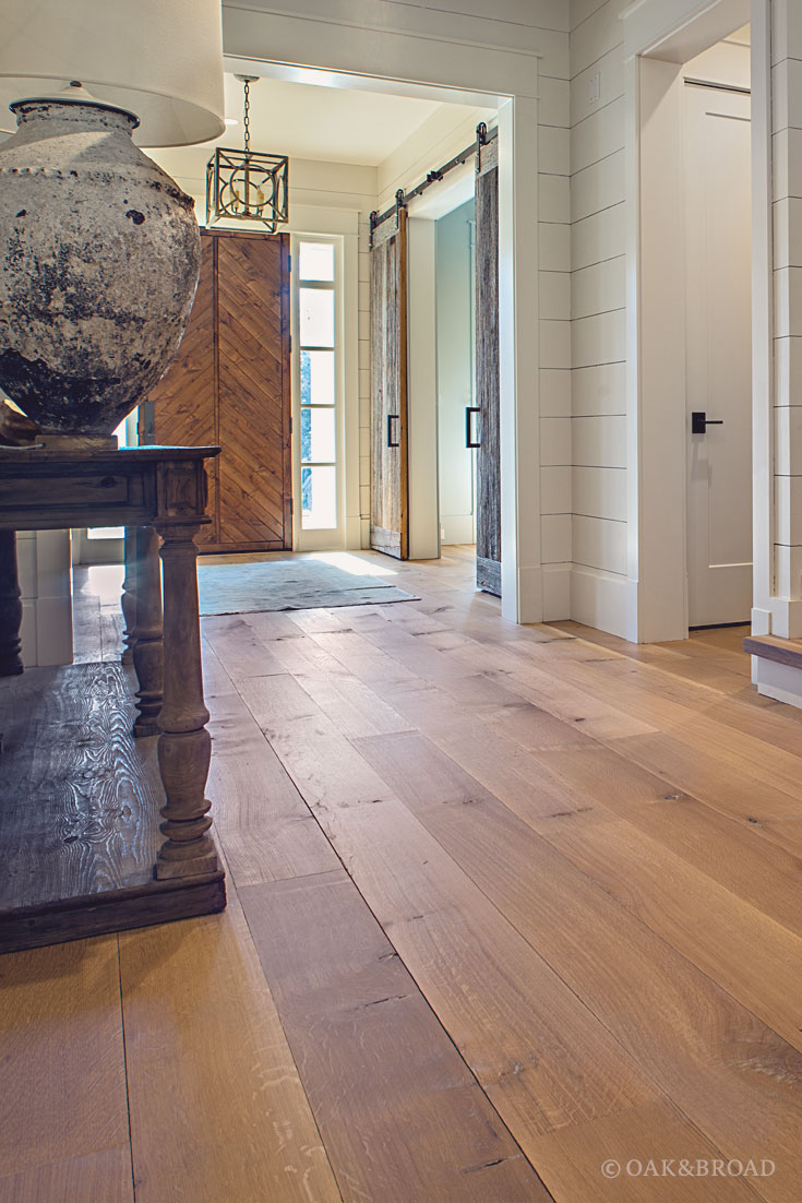 Wide Plank White Oak Hardwood Floor by Oak and Broad with Custom Stain | Entryway with custom reclaimed style wood door and iron door hardware