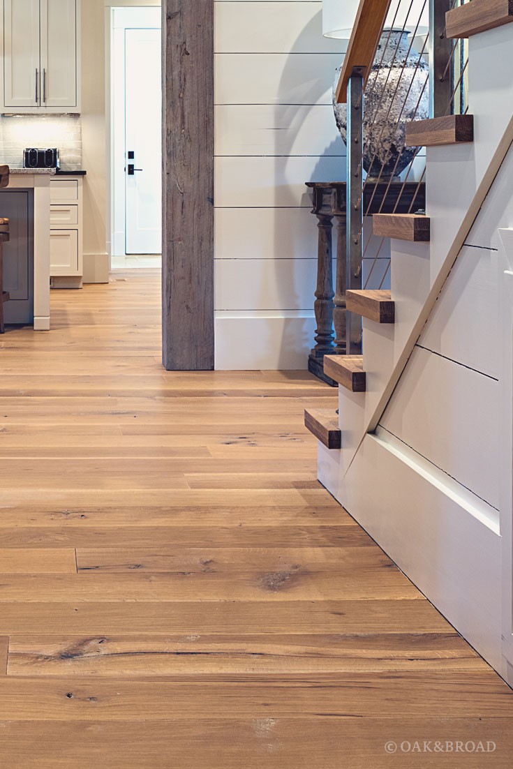 Wide Plank White Oak Hardwood Floor by Oak and Broad with Custom Stain | Detail of matching wood stair treads and wide plank paneling