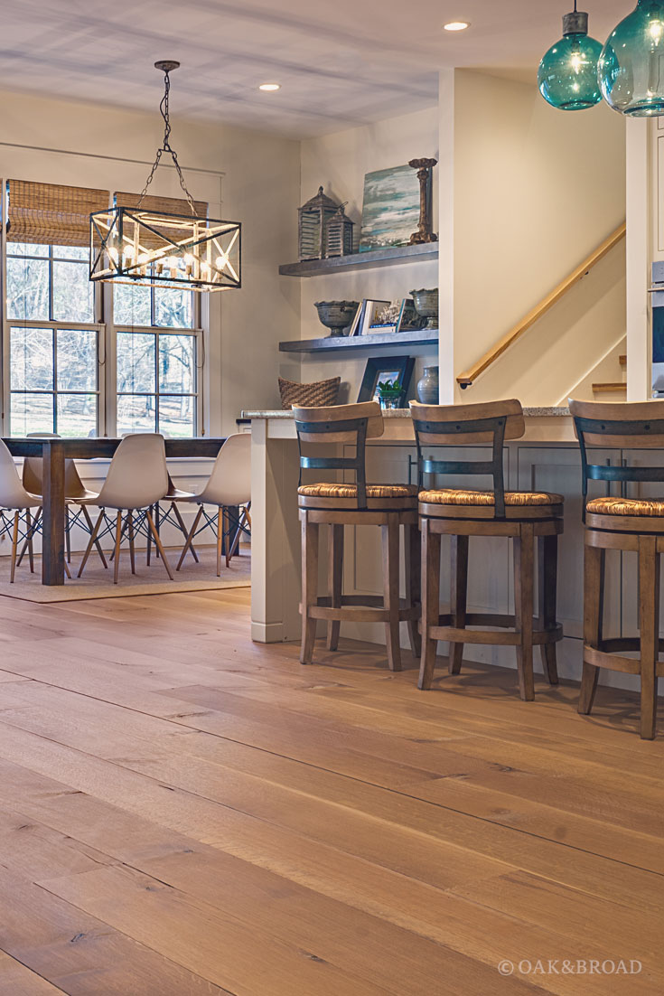 Wide Plank White Oak Hardwood Floor by Oak and Broad with Custom Stain | View from rustic modern kitchen into dining area with Eames chairs and geometric chandelier over dining table
