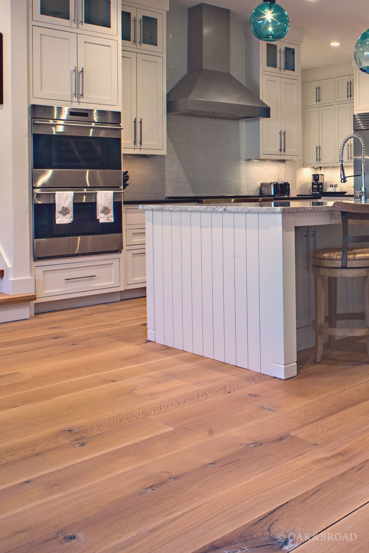 Wide Plank White Oak Hardwood Floor by Oak and Broad with Custom Stain | Rustic modern kitchen with stainless steel appliances and hood