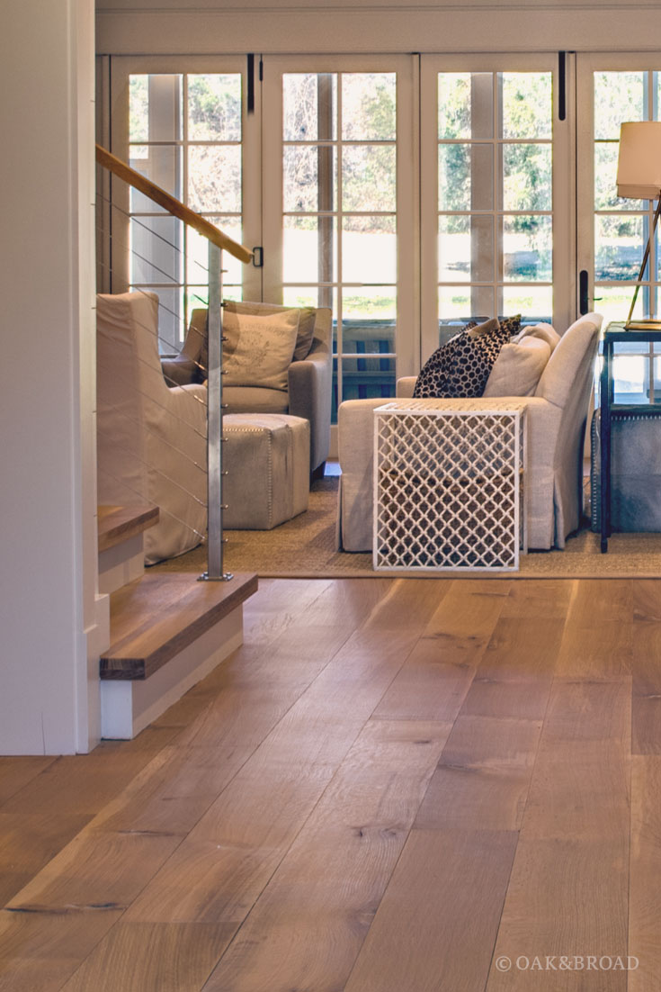 Wide Plank White Oak Hardwood Floor by Oak and Broad with Custom Stain | View into living room with matching stair treads