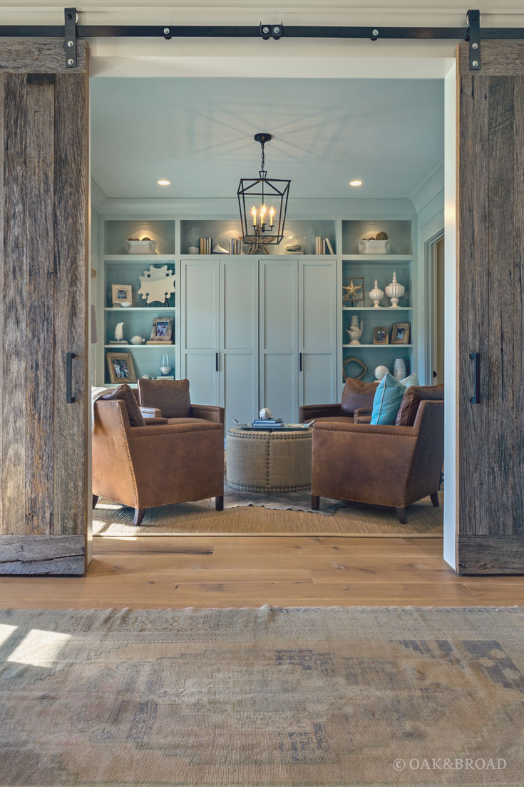 Wide Plank White Oak Hardwood Floor by Oak and Broad with Custom Stain | View from entryway to living area with built-in shelving, reclaimed style wood, and teal paint in background