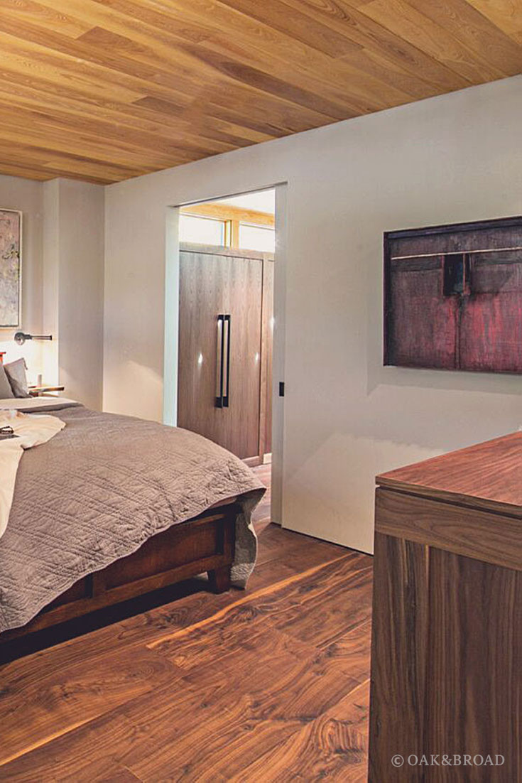 Wide Plank Black Walnut Hardwood Floor by Oak and Broad | modern bedroom with wooden paneling on ceiling, purple artwork