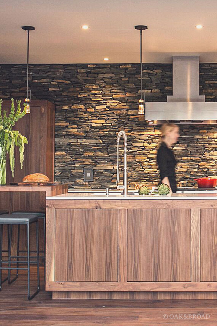 Wide Plank Black Walnut Hardwood Floor by Oak and Broad | Person in modern kitchen with walnut, stone, and stainless finishing