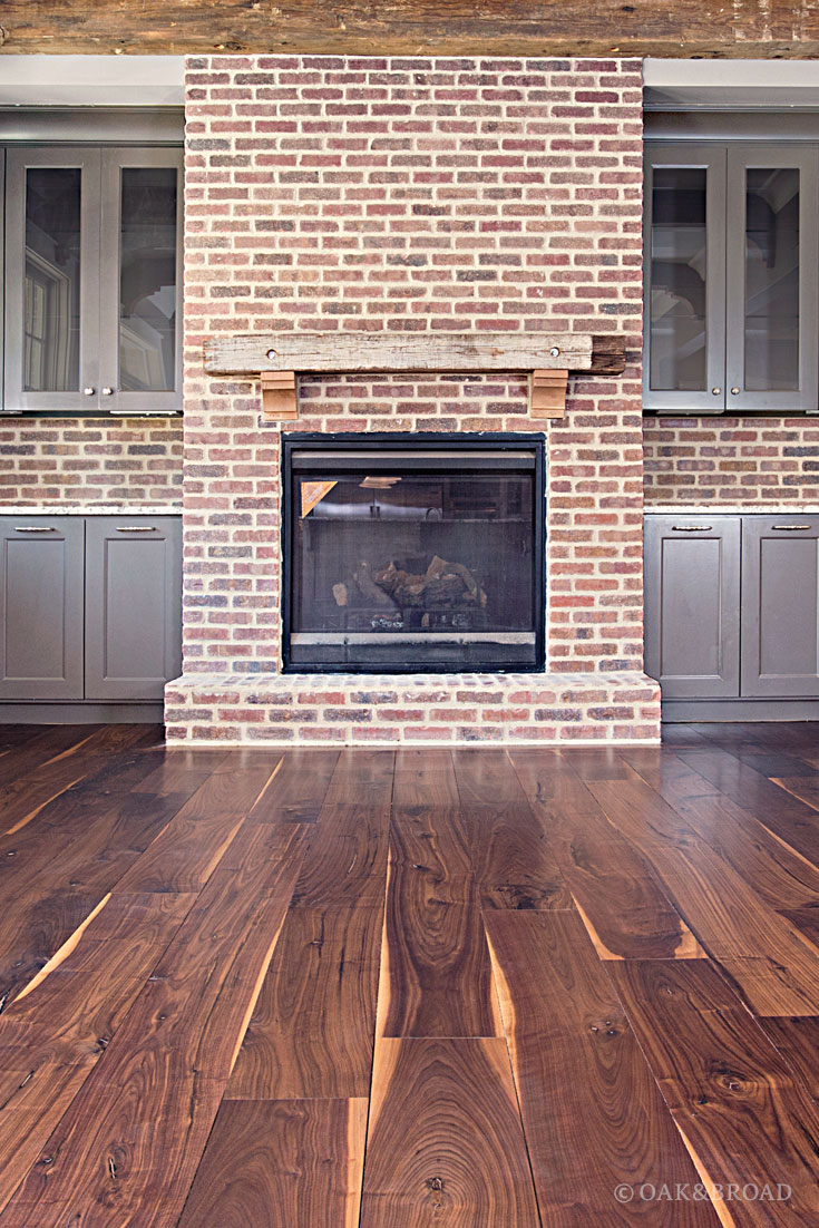 Wide Plank Black Walnut Hardwood Floor By Oak And Broad | Rustic Character Grade | Living Room with Fireplace and Heart Pine Beams