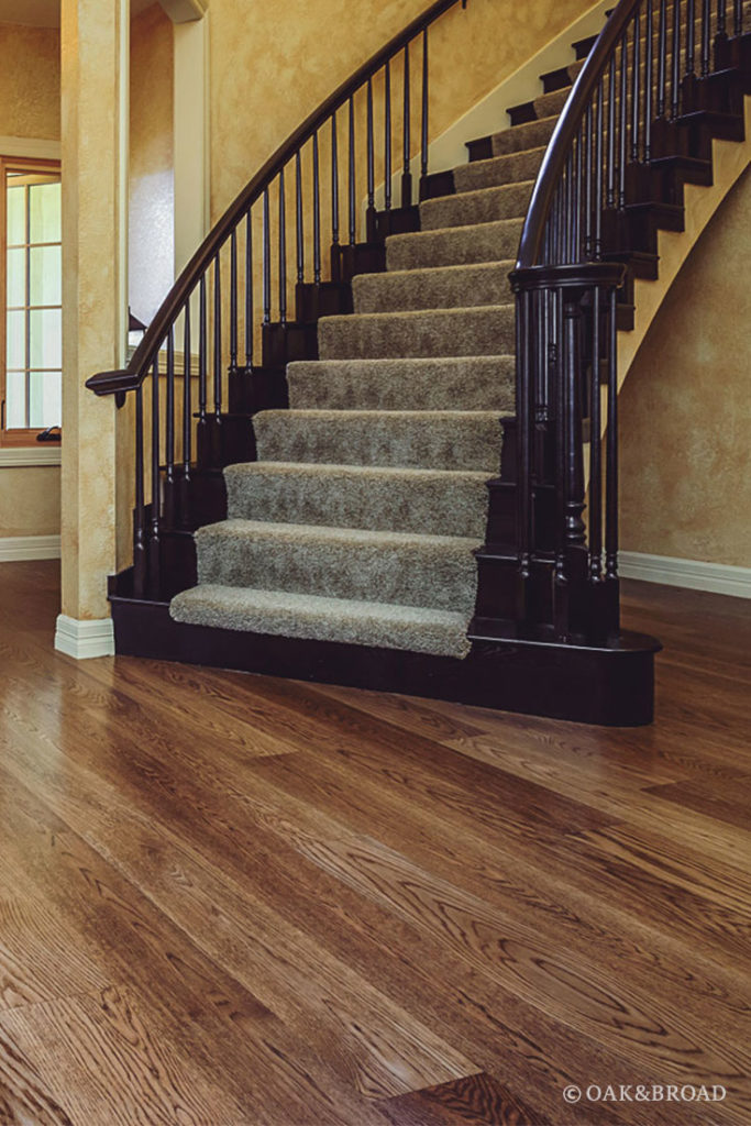 Stairway next to wide plank hardwood floor by Oak & Broad