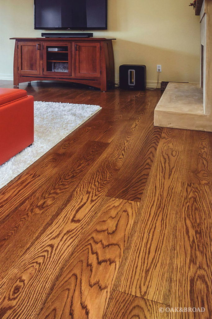 Living room with wide plank hardwood floor by Oak and Broad